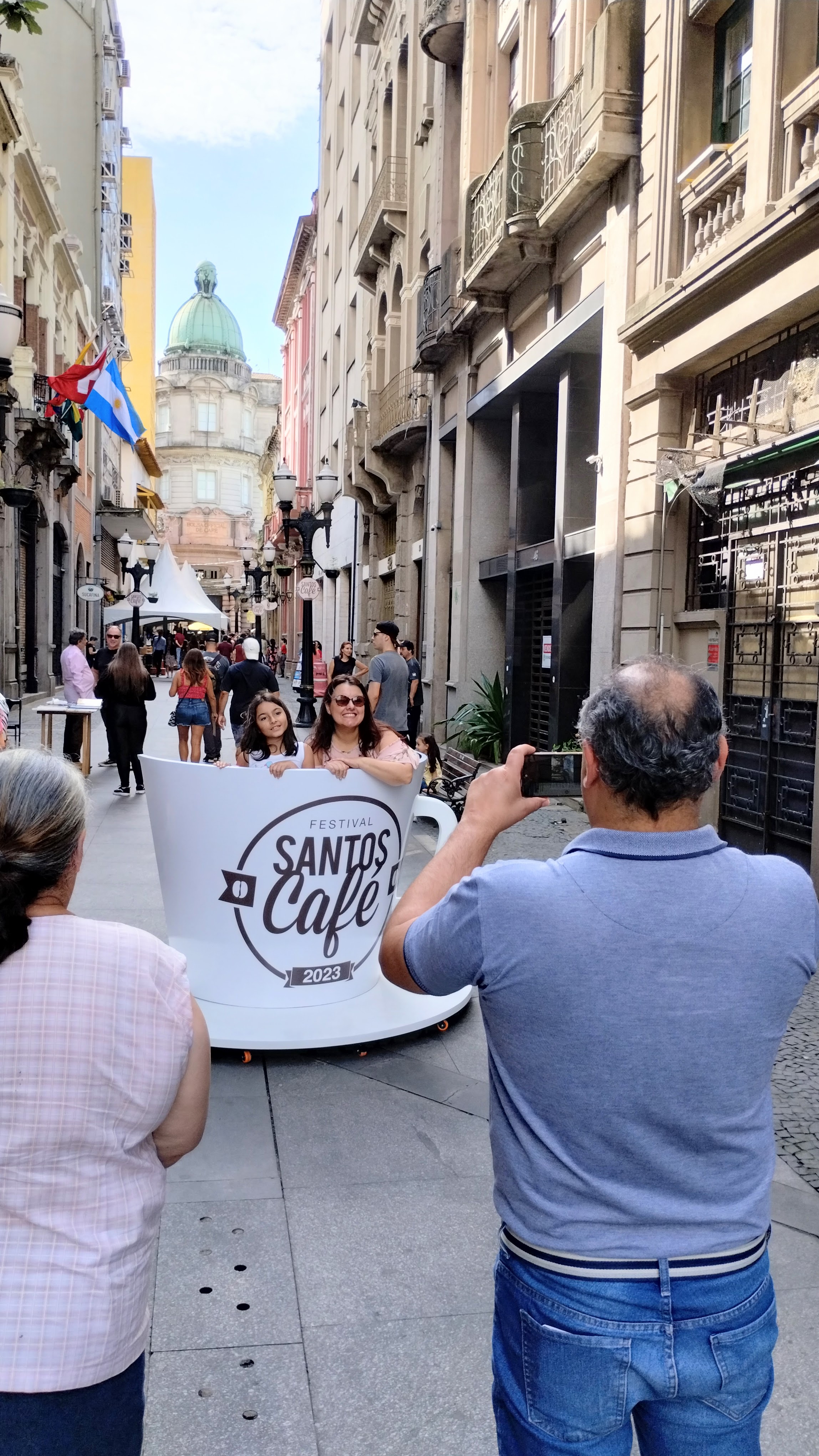 Pessoas tirando foto dentro de grande xícara instagramável, no bulevar da Rua XV de Novembro, durante o Festival Santos Café