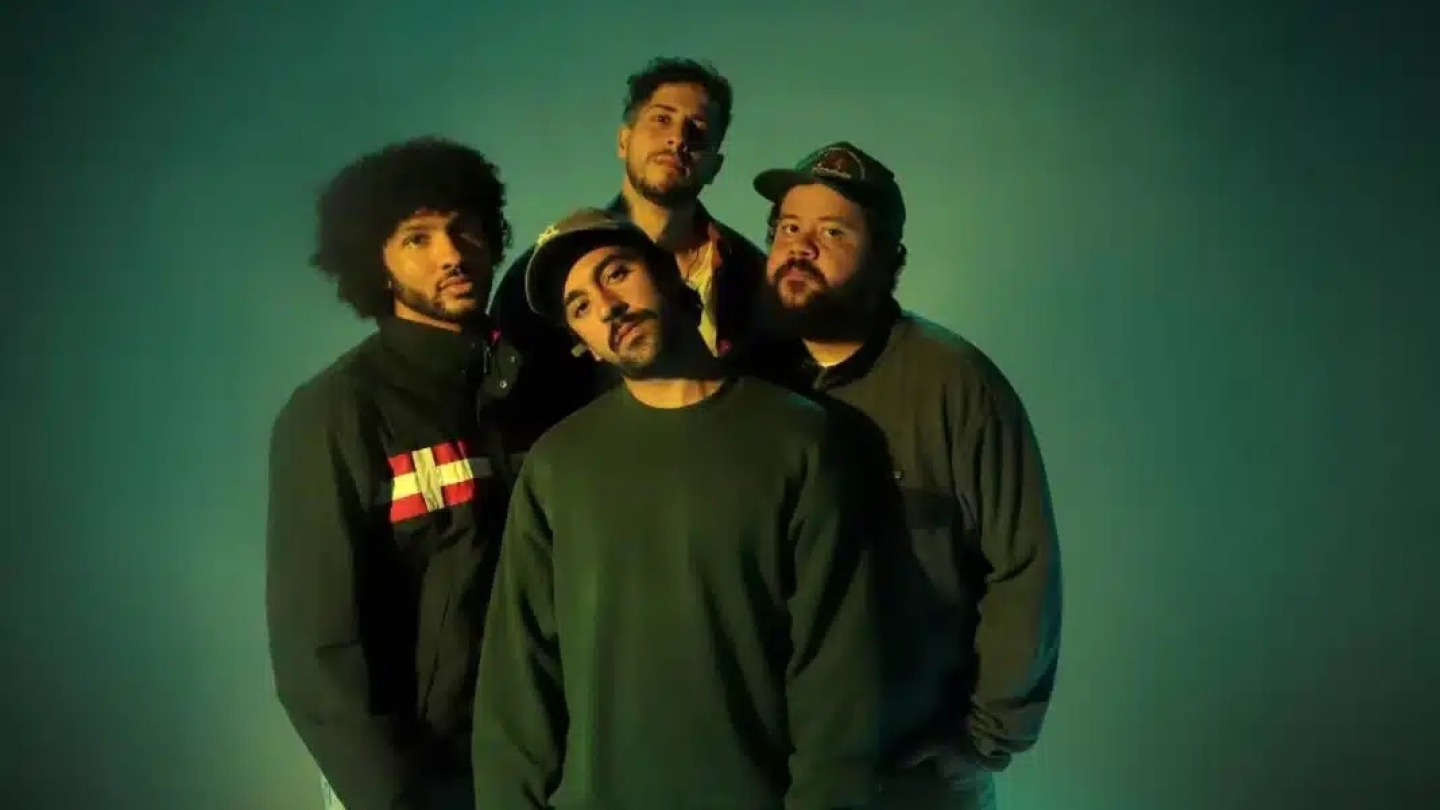 Quatro integrantes da banda brasileira Zimbra posam para uma foto promocional sob uma iluminação dramática em tons de verde e azul