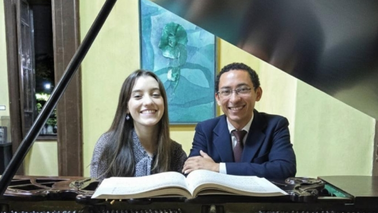 Cartaz de divulgação do Recital de Piano do Duo Libenaro, com fotografia dos pianistas posando diante de um piano de cauda. O evento acontece em 20 de junho de 2026, às 17h, com entrada gratuita.