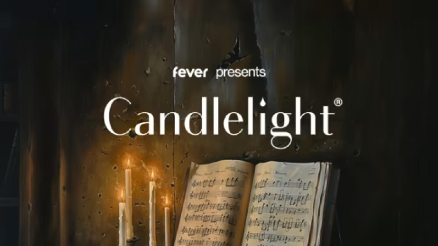 Arte promocional da série de concertos Candlelight, apresentada pela plataforma Fever. A composição retrata um ambiente clássico e intimista, iluminado pela luz suave de velas. Em destaque, há um livro de partituras aberto sobre uma mesa de madeira, cercado por folhas musicais e castiçais acesos, criando uma atmosfera de contemplação e elegância.