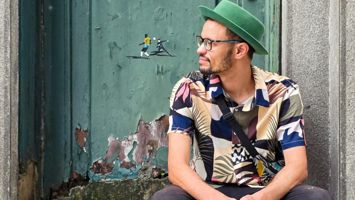 Artista Preo ao lado de uma obra de sua autoria, de arte urbana