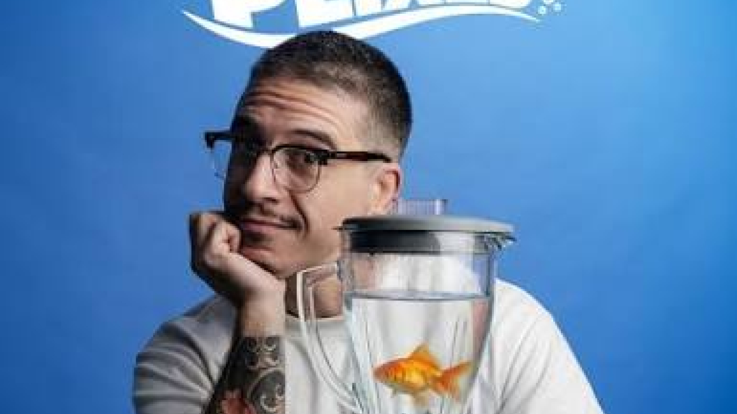 Cartaz promocional do espetáculo "Patrick Maia Não Respeita os Peixes". O humorista Patrick Maia aparece apoiando o rosto em uma das mãos, com expressão divertida e pensativa, enquanto segura um liquidificador contendo um peixe dourado. Vestido com camiseta branca, óculos e exibindo tatuagens nos braços, ele contrasta com o fundo azul vibrante. Na parte superior, o título do show aparece em letras brancas estilizadas, reforçando o tom irreverente da apresentação.