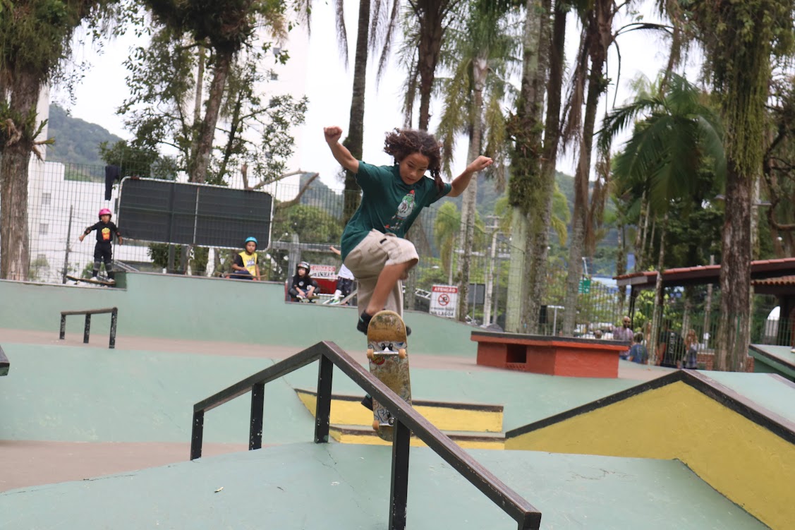 A young skateboarder performs a trick on a rail at the Lagoa da Saudade skate park