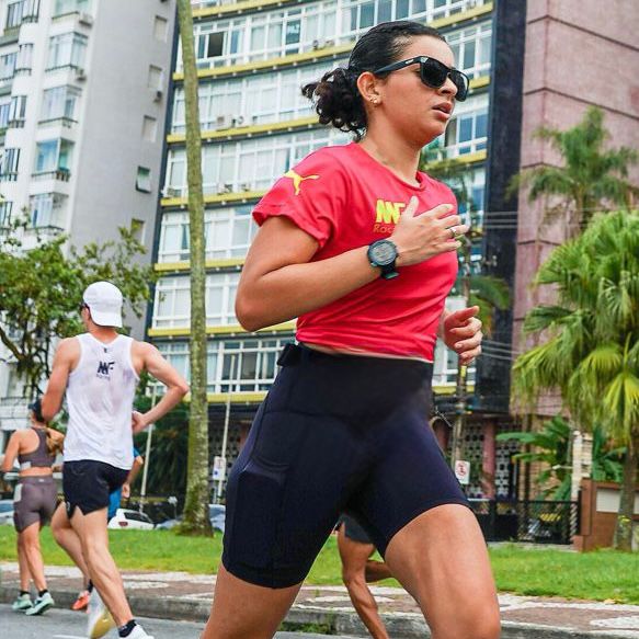 Corredora com blusa vermelha, shorts preto e óculos escuros