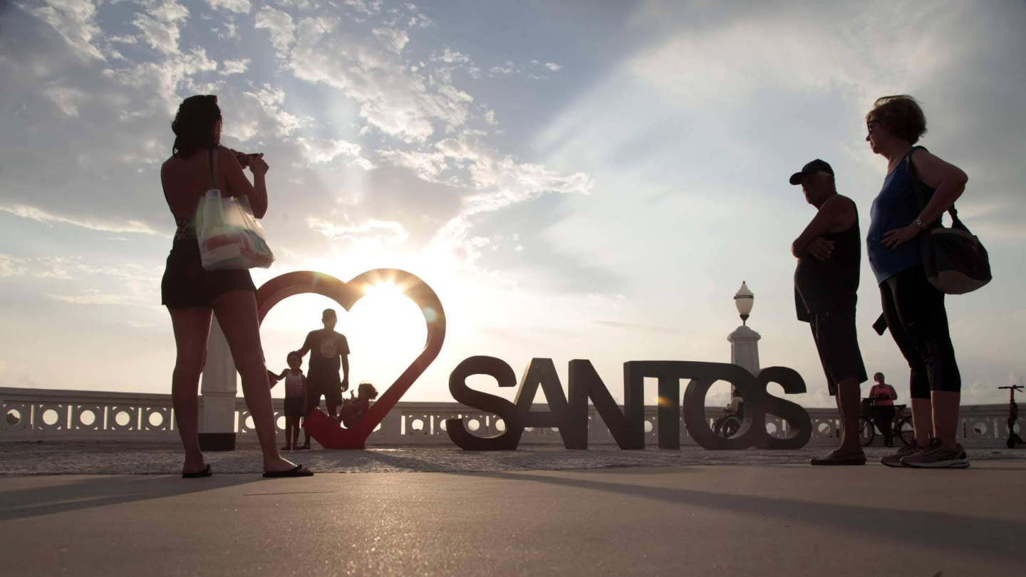 Pessoas em torno da escultura Amo Santos, da Ponta da Praia, ao entardecer