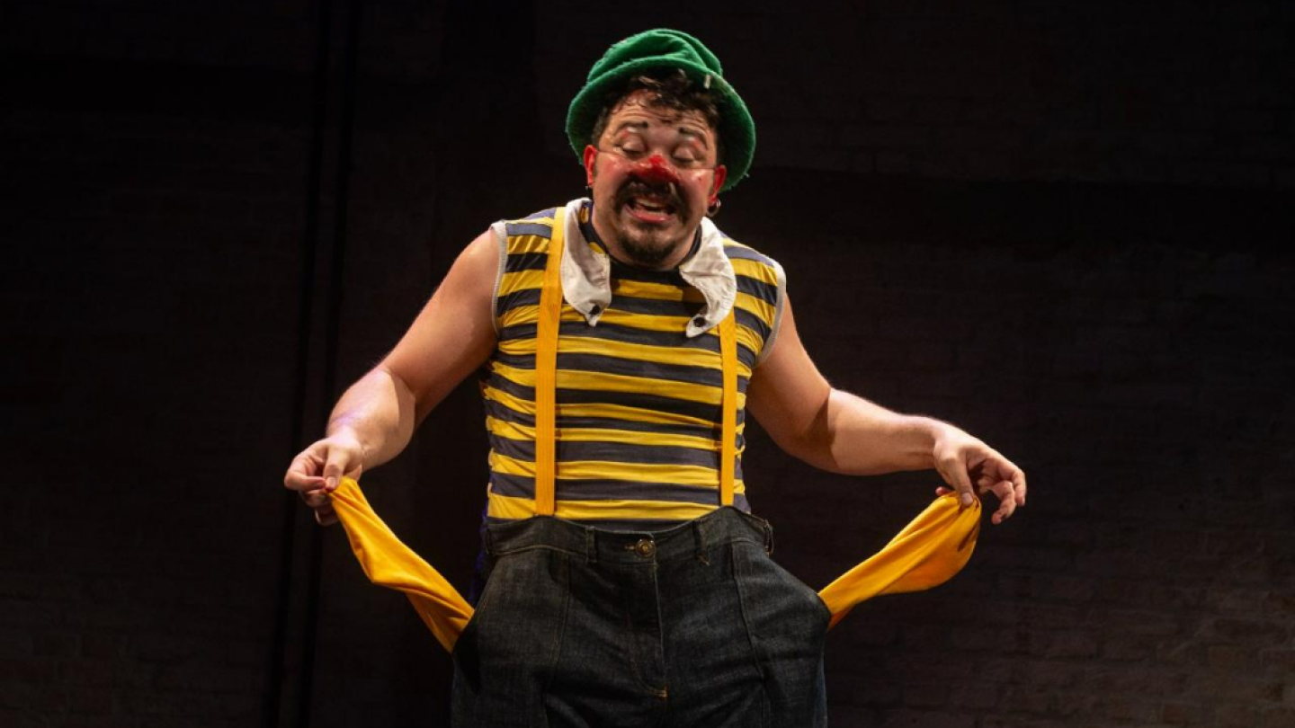 Palhaço com expressão preocupada, segurando os bolsos vazios da calça