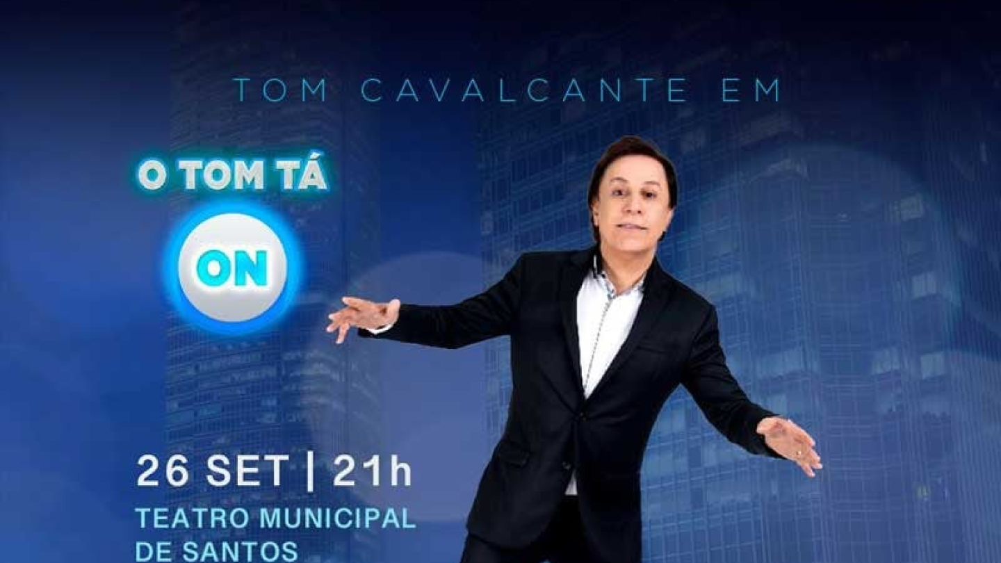 Comediante Tom Cavalcante, de roupa preta, equilibrado num pé só, com fundo azul