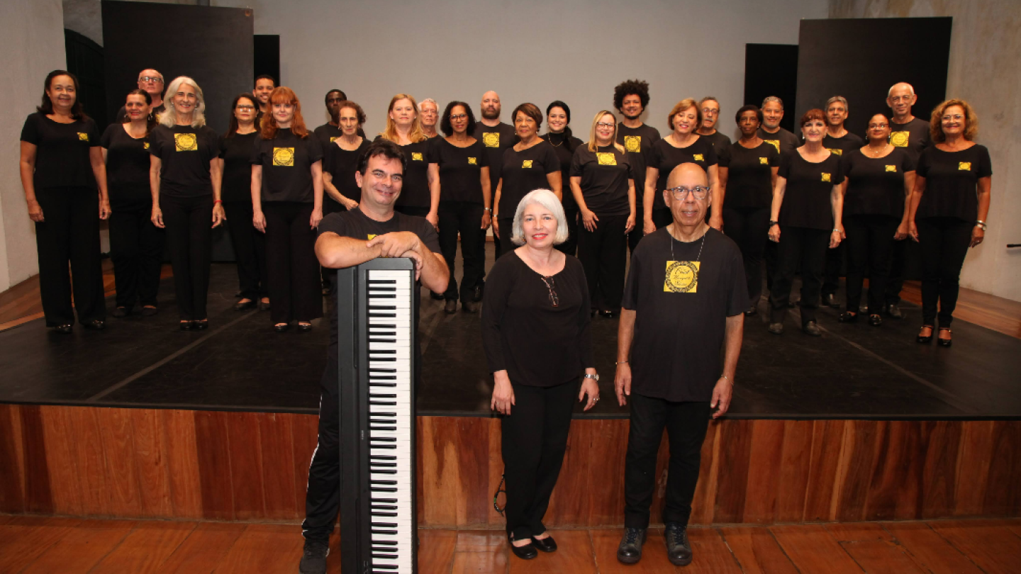 Coral com diversas pessoas em trajes pretos, e um deles segurando um teclado