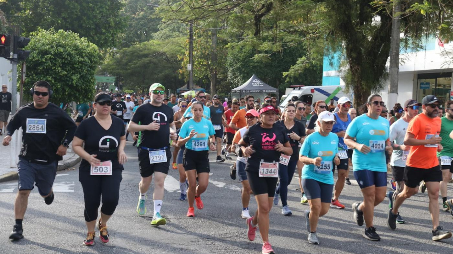 Diversas pessoas praticando corrida de rua, com roupas esportivas coloridas e árvores ao fundo