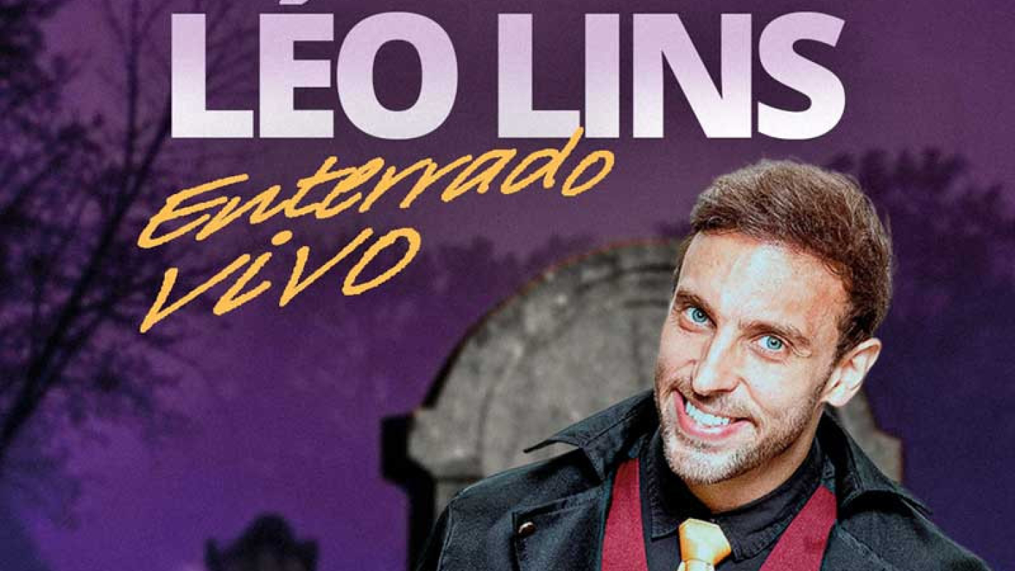 Cartaz do show de Léo Lins 'Enterrado Vivo', com o comediante de paletó preto, num cenário de lápides escuras