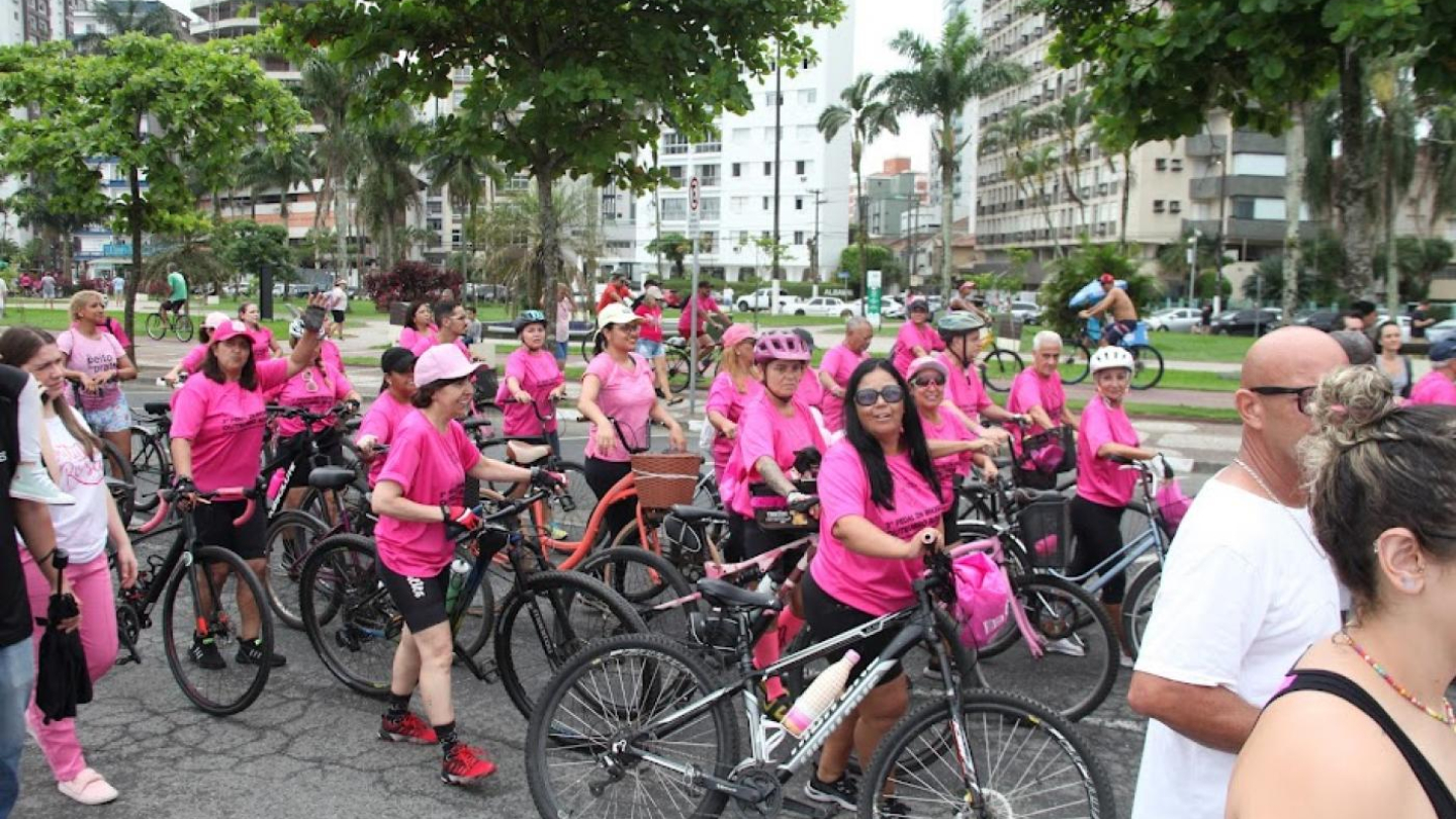 Diversos ciclistas, maioria mulheres, com bicicletas e camiseta rosa