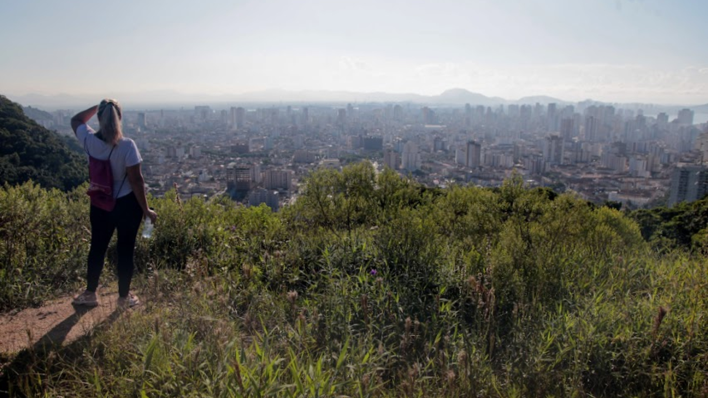 Mulher observando a vista da cidade do alto no morro