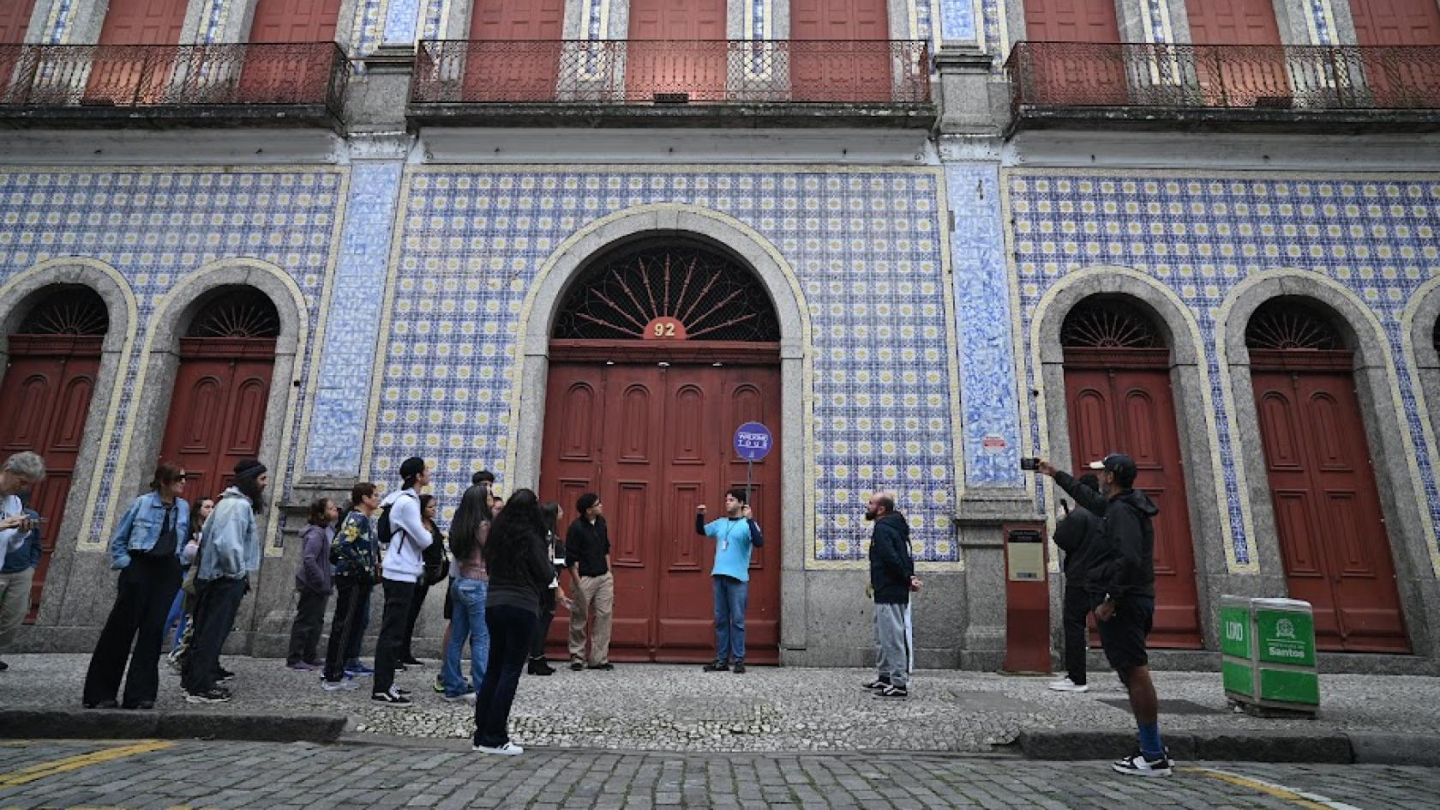 Grupo de pessoas em um "walking tour" (passeio a pé) ou visita guiada, reunido em frente a um imponente edifício histórico