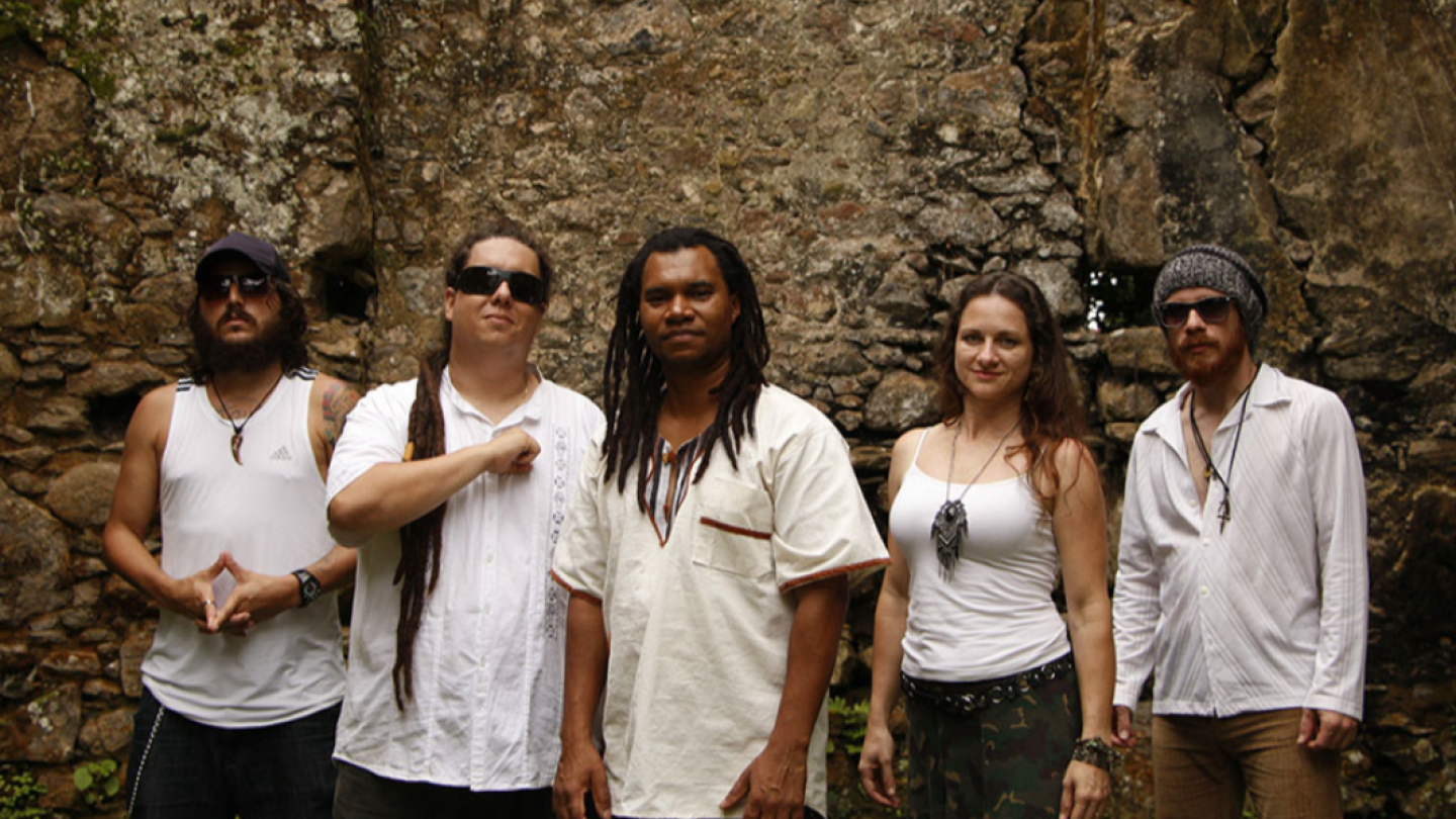 Os cinco integrantes da banda de reggae Afrodizia posam para uma foto em frente a uma rústica parede de pedras