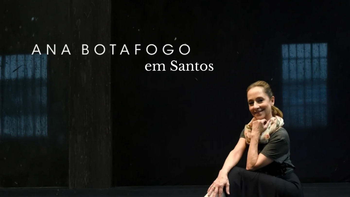 A imagem mostra a renomada bailarina brasileira Ana Botafogo sentada no chão de um palco, sorrindo para a câmera, com o texto "ANA BOTAFOGO em Santos" ao fundo