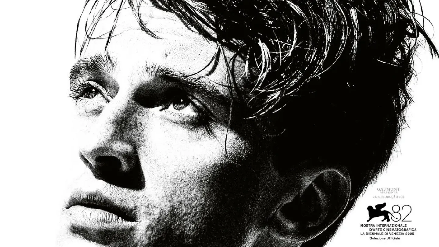 Cartaz do filme "O Estrangeiro", dirigido por François Ozon e inspirado na obra homônima de Albert Camus. A arte apresenta um retrato em preto e branco de um jovem olhando para o alto, com expressão séria e contemplativa. O título surge em grandes letras vermelhas na parte inferior, contrastando com o fundo claro. À direita, aparecem os nomes do elenco principal e selos destacam a participação do longa na Mostra Internacional de Arte Cinematográfica de Veneza. A composição minimalista e o forte contraste vi